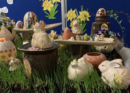 Ozdoby wielkanocne z ceramiki ustawione na stole w trawniku z młodego owsa.