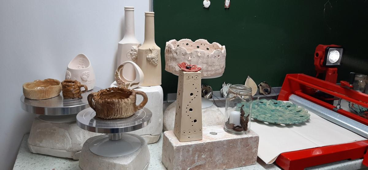 Wyroby gliniane ustawione na stole udekorowanym korą drzewa.