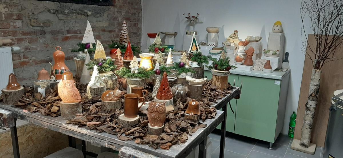 Wyroby gliniane ustawione na stole udekorowanym korą drzewa.