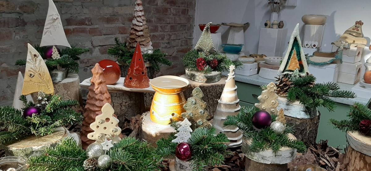 Wyroby gliniane ustawione na stole udekorowanym korą drzewa.