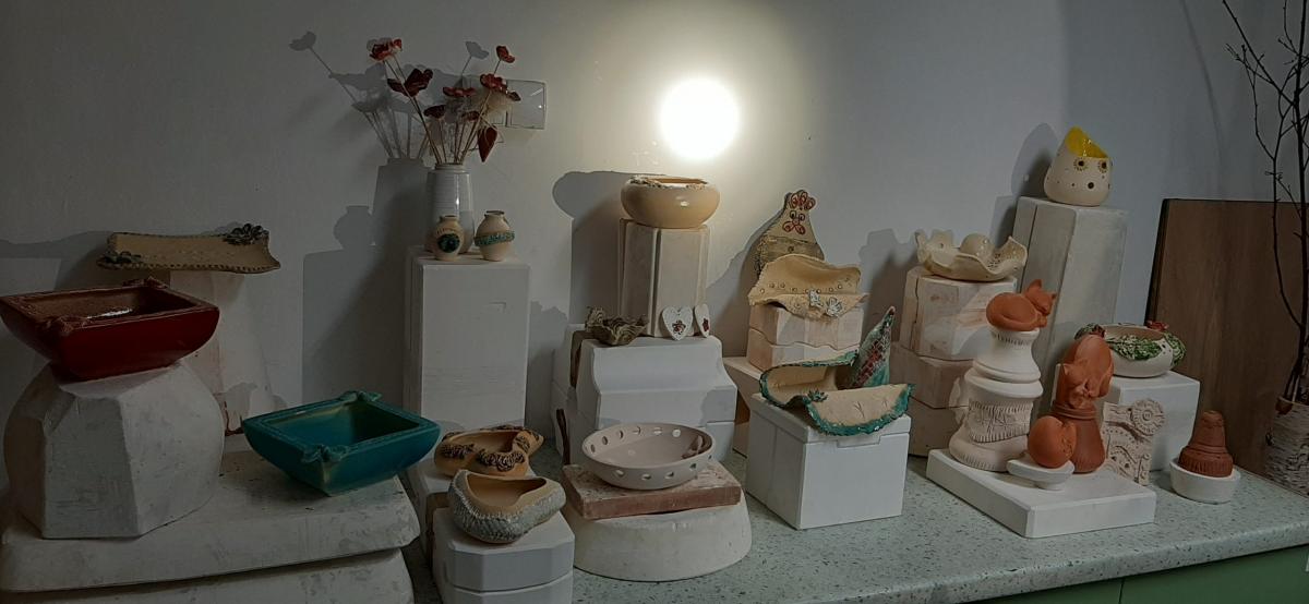 Wyroby gliniane ustawione na stole udekorowanym korą drzewa.