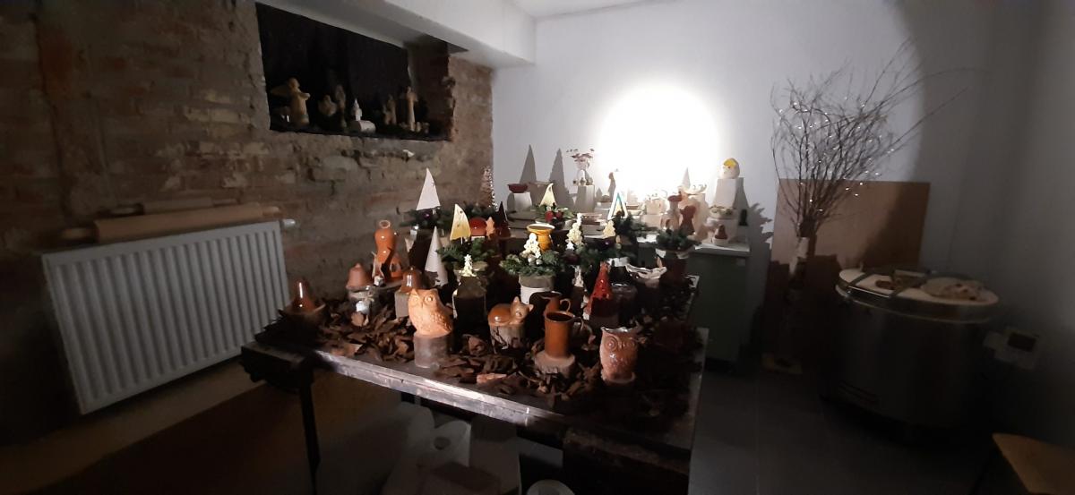 Wyroby gliniane ustawione na stole udekorowanym korą drzewa.