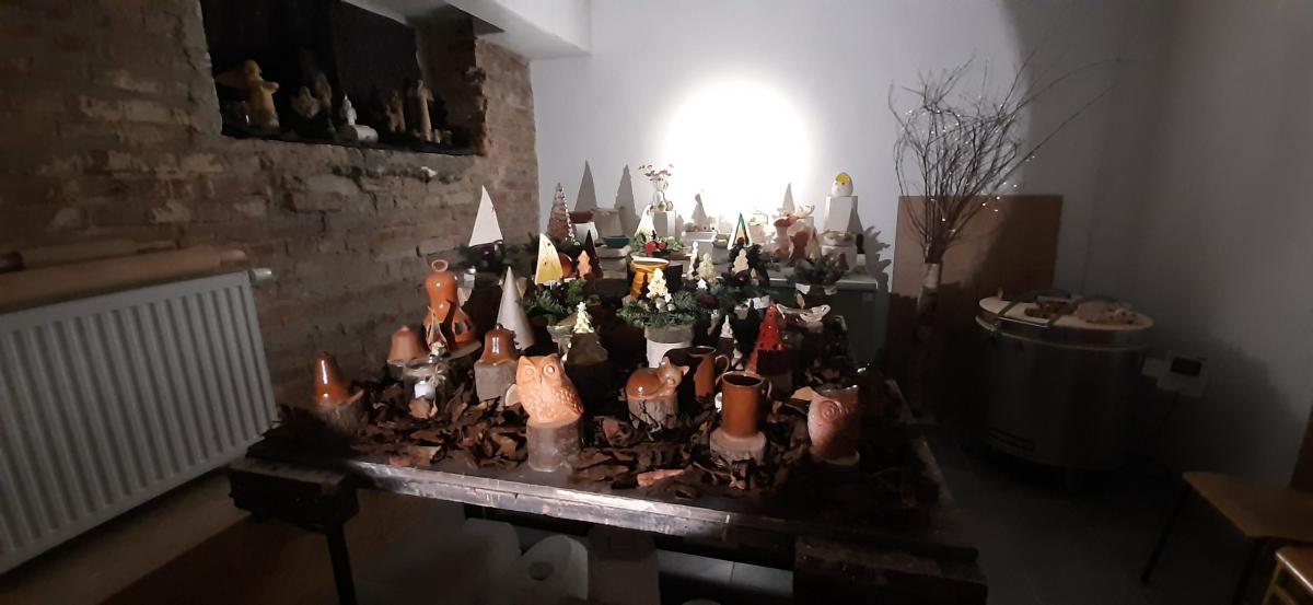 Wyroby gliniane ustawione na stole udekorowanym korą drzewa.