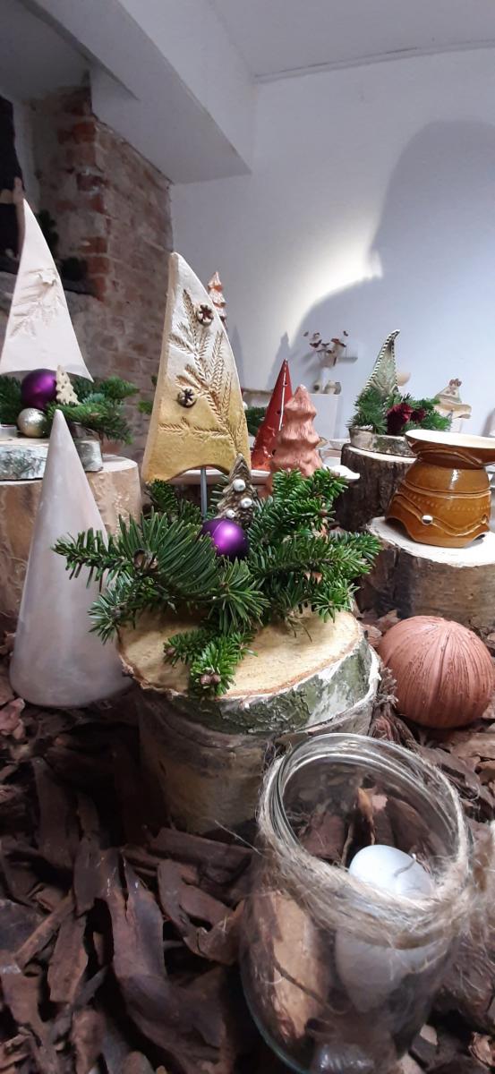 Wyroby gliniane ustawione na stole udekorowanym korą drzewa.