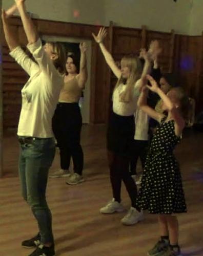 Grupa dziewcząt stoi z uniesionymi do góry rękami.