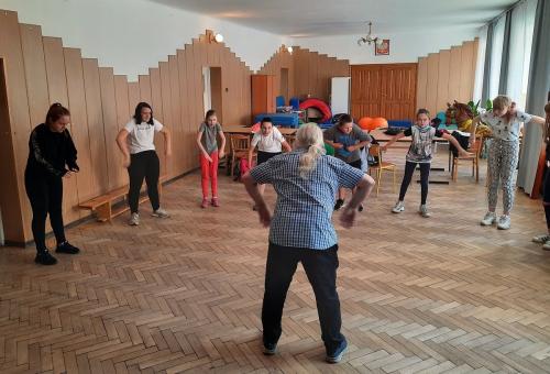 Grupa dzieci naśladuje ruchy dorosłego mężczyzny.