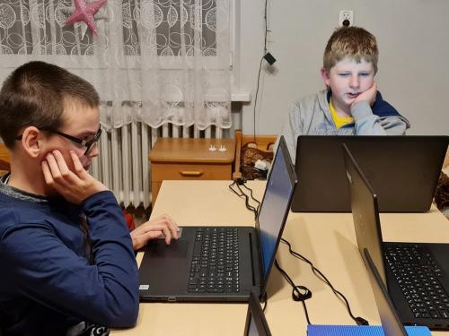 Dwóch chłopców spogląda na ekrany laptopów.