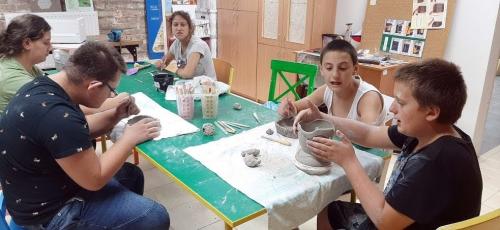 Grupa młodzieży wykonuje ozdoby z gliny.