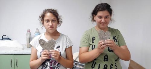 Dwie dziewczynki pokazuje serca z gliny.