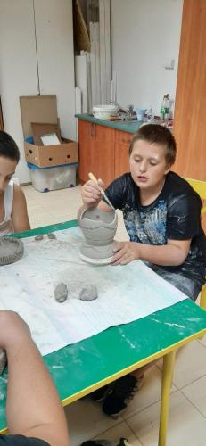 Chłopiec rzeźbi w glinie.