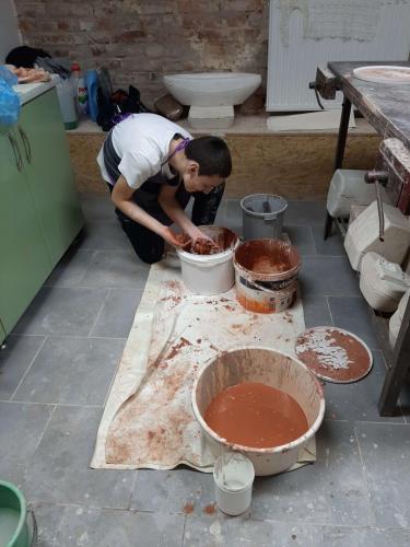 Chłopiec pochyla się nad wiaderkami ze szkliwem.