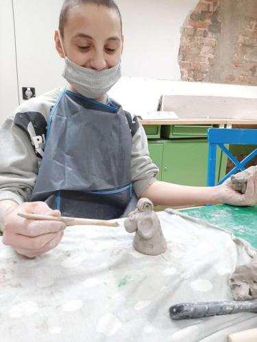 chłopiec formuje baranka z gliny.