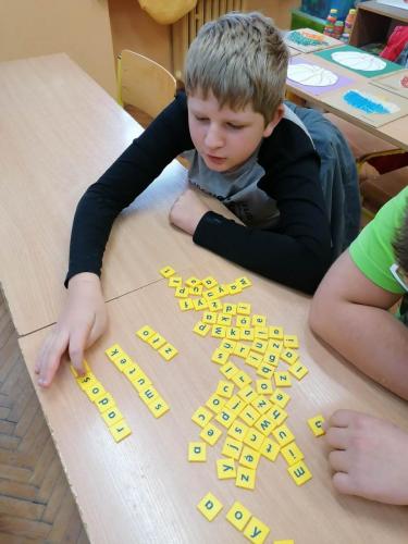 Chłopiec układa napisy z żółtych klocków.