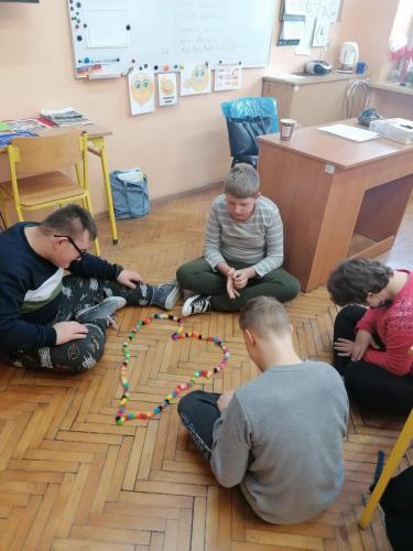 Czworo dzieci siedzi na podłodze i układa serce z bunchamsów.