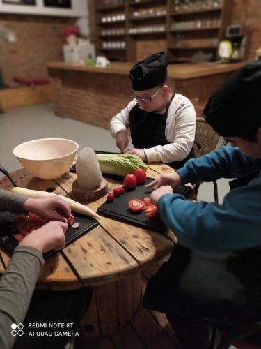 Troje dzieci kroi warzywa przy stole.