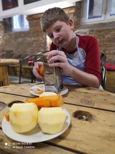 Chłopiec trze na tarce jabłka.