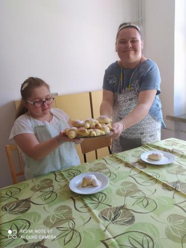 Dziewczynka podaje drugiej dziewczynce talerz z rogalikami.