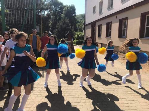 Grupa dziewcząt w niebieskich strojach czirliderek trzyma w dłoniach pompony.