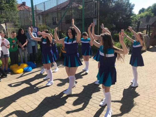 Grupa dziewcząt w strojach czirliderek tańczy.