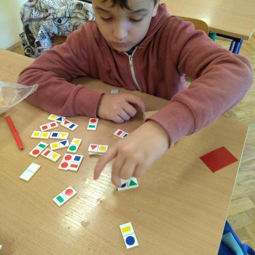 Chłopiec przy stoliku układa domino obrazkowe.