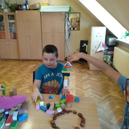 Chłopiec układa kolorowe drewniane klocki. Buduje wieżę